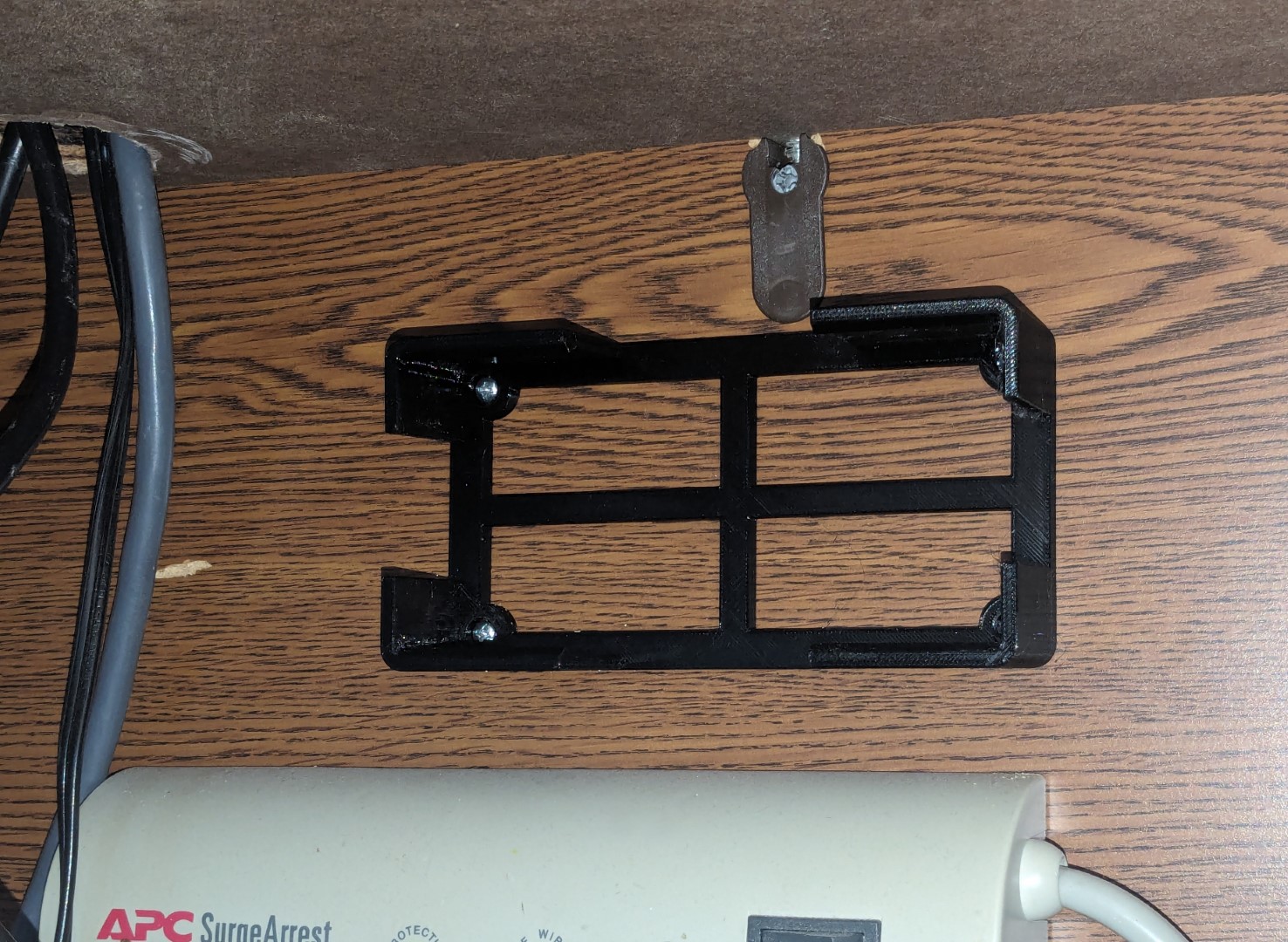 An attached mount under the computer desk, waiting to be fitted with a bulky power brick.